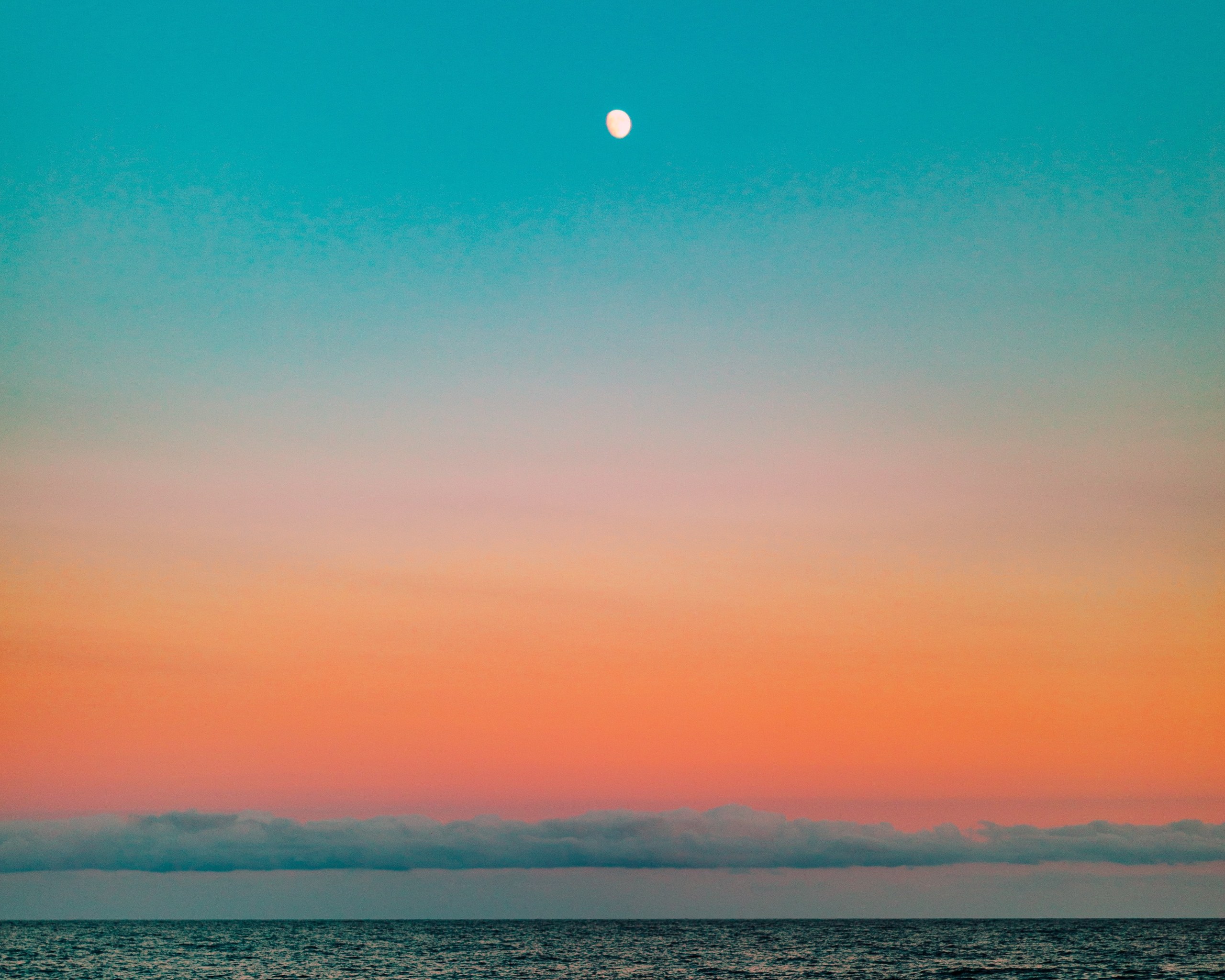 Sky that goes from top to bottom, to the horizon of the sea, cyan, light blue, pink, orange to an intense reddish color.
