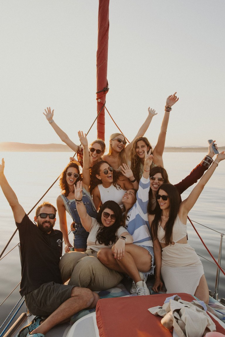 Grupo de amigos en Velero Assol en Sotogrande, Alquiler de velero privado al atardecer del velero rojo